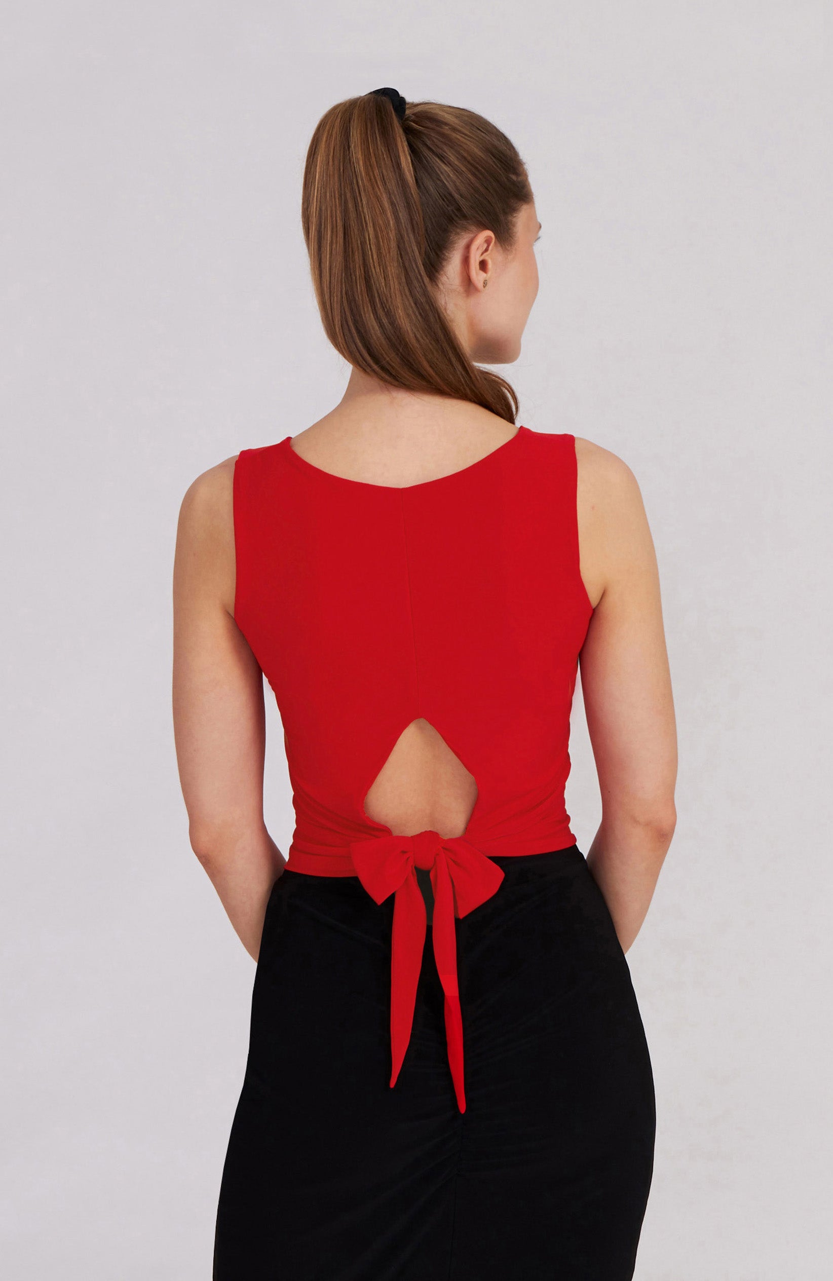 Model wearing the ZOE red tango top with a back bow detail on the dance floor.